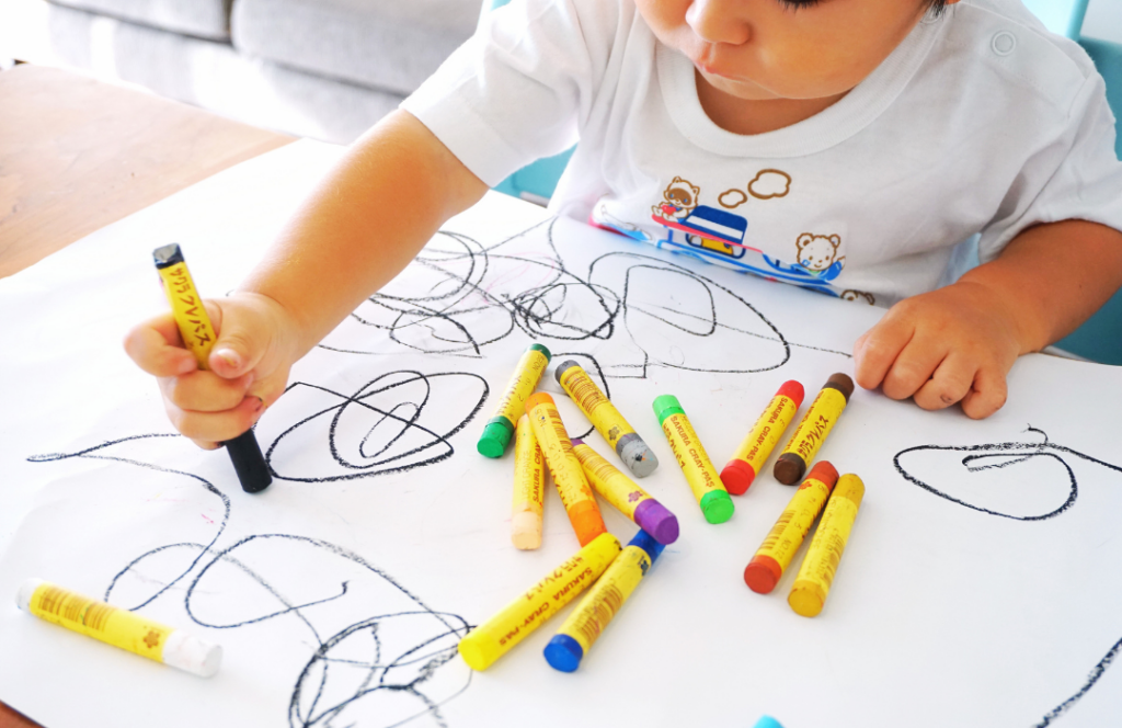 Fine motor development ages 1-3 years old toddler scribbling with crayons